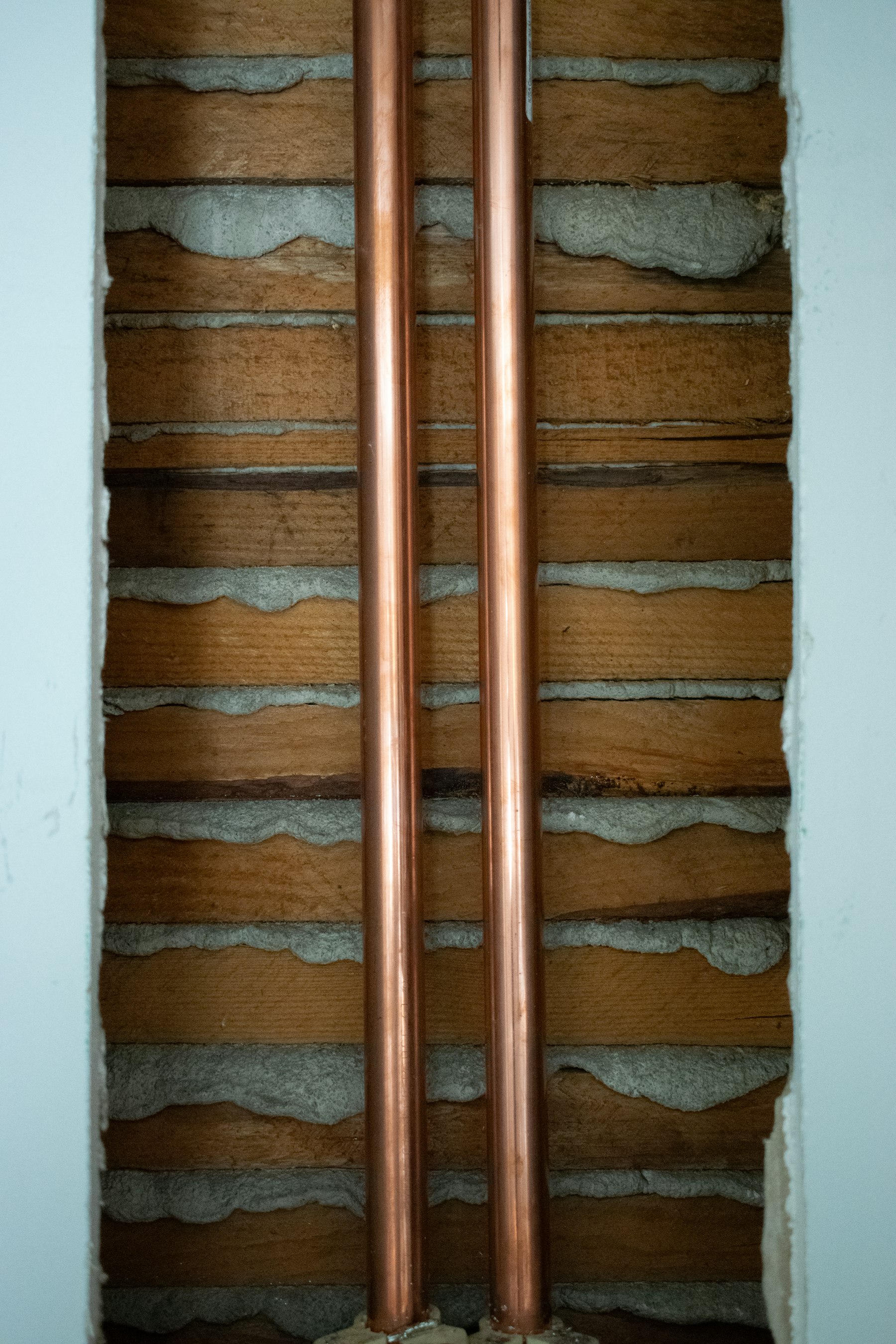 Vertical copper supply pipes exposed in a wall cutaway